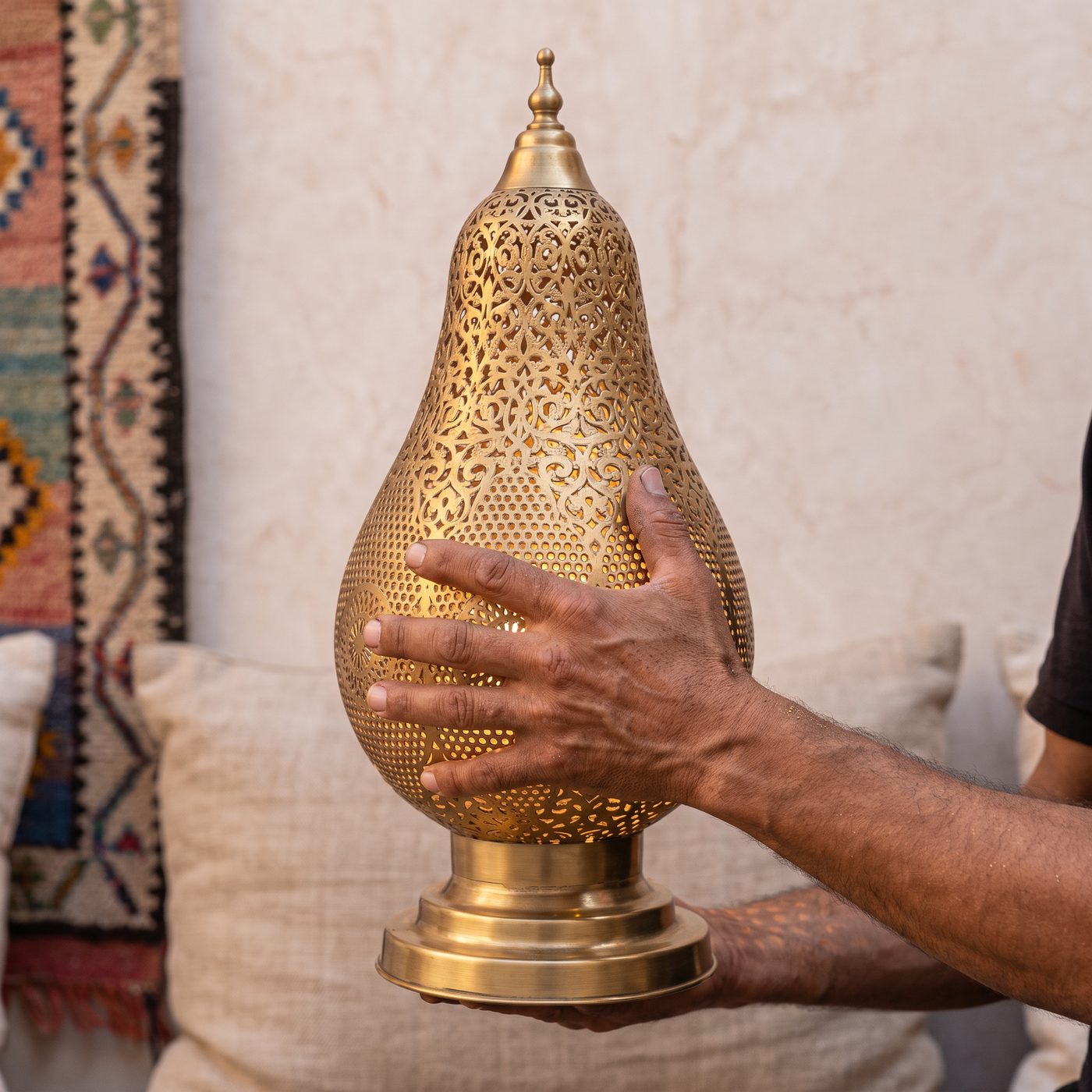 An artisan holding a hand-pierced brass table lamp